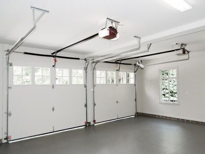 Empty clean garage interior with large white door and windows