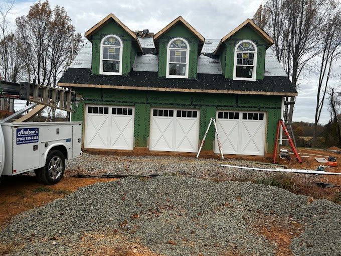 Green three-car garage under construction with white doors and windows