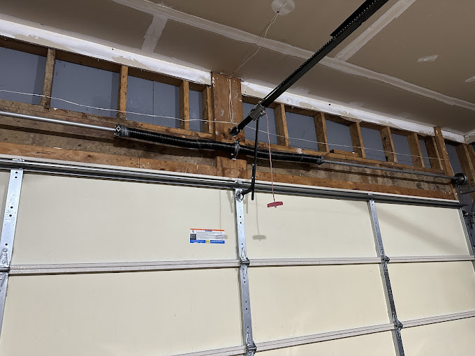 Garage door under construction with exposed wooden framing and mounting hardware